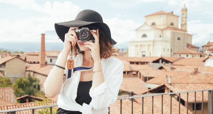 Frau, die ein Foto macht und auf eine europäische Stadtlandschaft mit einer Kirche blickt.