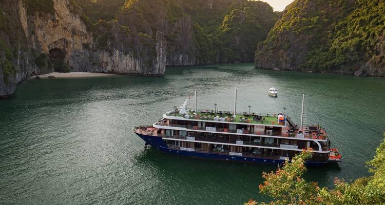 Barco de crucero en una bahía pintoresca con formaciones de piedra caliza.
