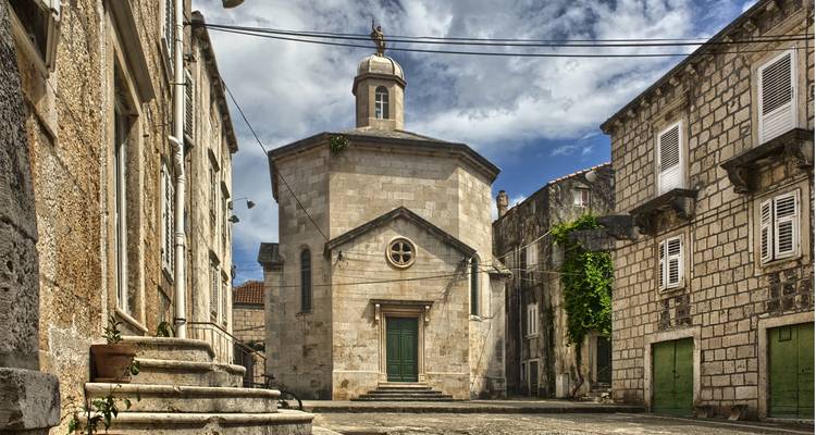 Iglesia histórica de piedra en un patio empedrado.
