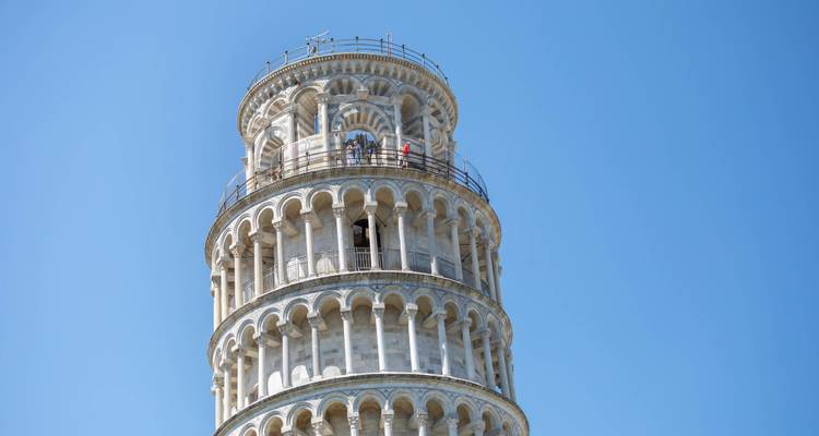Nahaufnahme der oberen Bögen und der Aussichtsplattform des Schiefen Turms von Pisa vor einem klaren blauen Himmel.