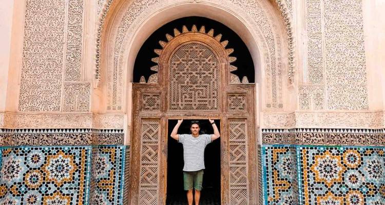 Una persona parada en una entrada ornamentada con patrones intrincados.