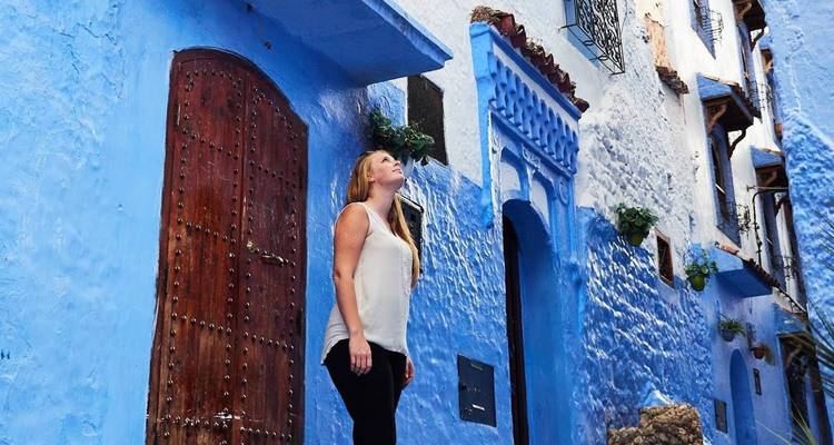 Una mujer mirando hacia arriba en una calle pintada de azul de Chefchaouen.