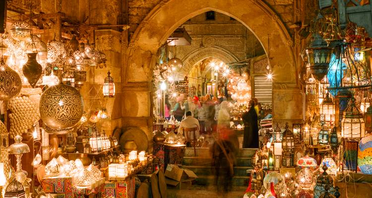 Paso iluminado con linternas doradas del bazar Khan el-Khalili lleno de compradores borrosos zumbando de vida por la noche
