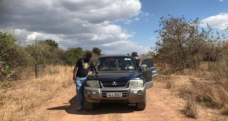 Man standing beside a 4x4 vehicle on a dirt road.