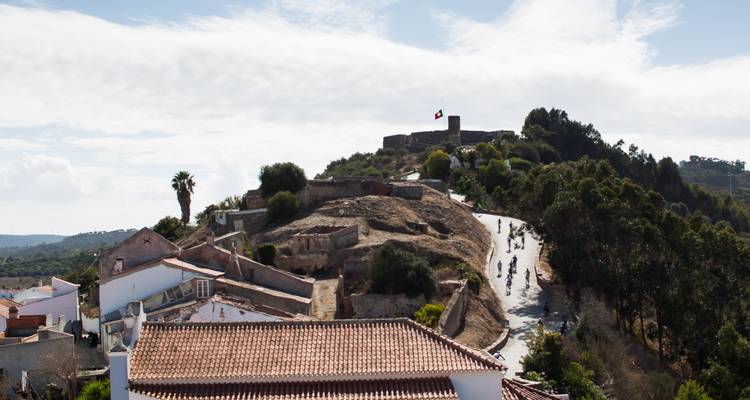 Colina histórica con ruinas y bandera portuguesa ondeando.
