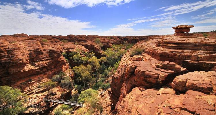Ruige rode rotsformaties met groen in een canyon.