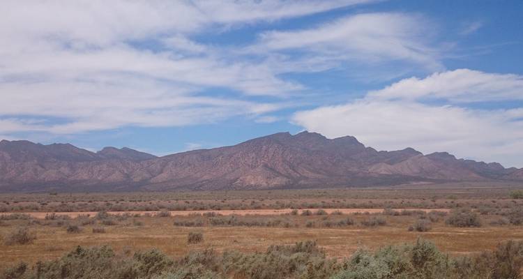Een weids uitzicht op een bergketen onder een blauwe hemel.