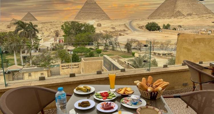 Una terraza con un desayuno preparado con vista a las Pirámides de Giza.