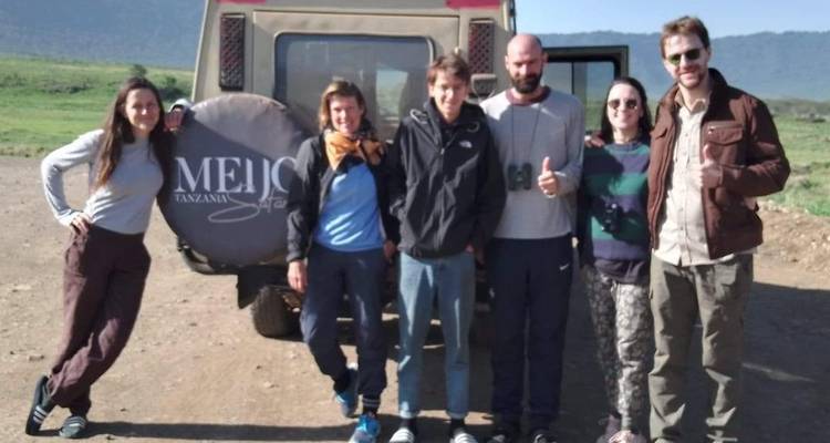 Groep mensen poserend voor een safariwagen.