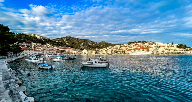 Bateaux amarrés dans un port avec une ville pittoresque en arrière-plan.