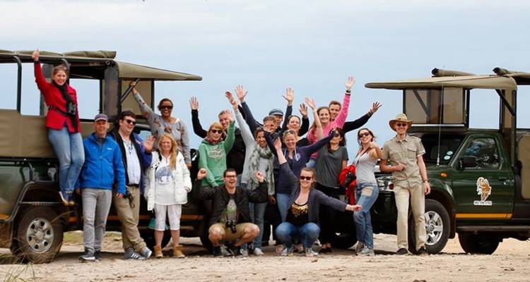 Grupo posando para una foto frente a jeeps de safari.