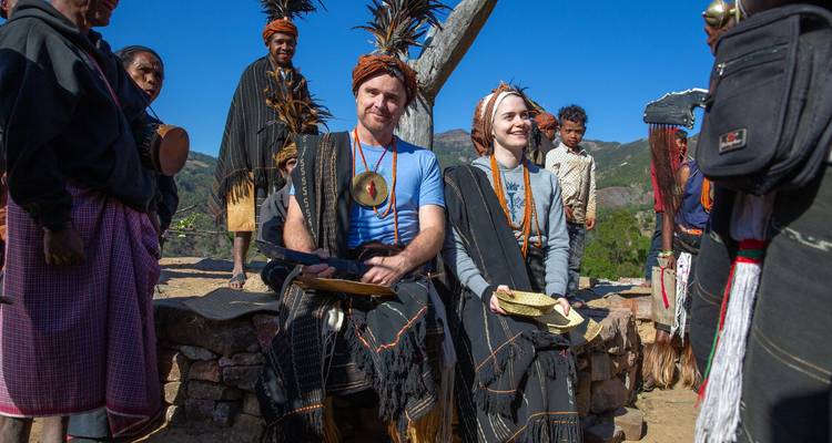 Travellers dressed in traditional Timorese attire participate in a cultural ceremony outdoors.