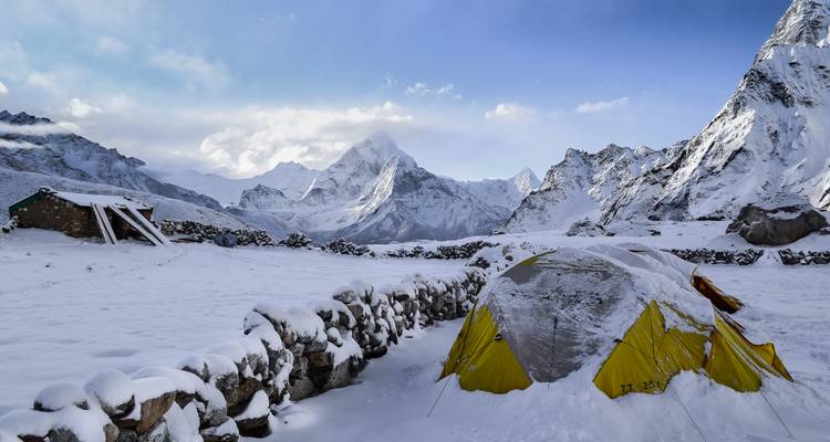 A tent set up in a snowy mountain landscape under a clear sky.