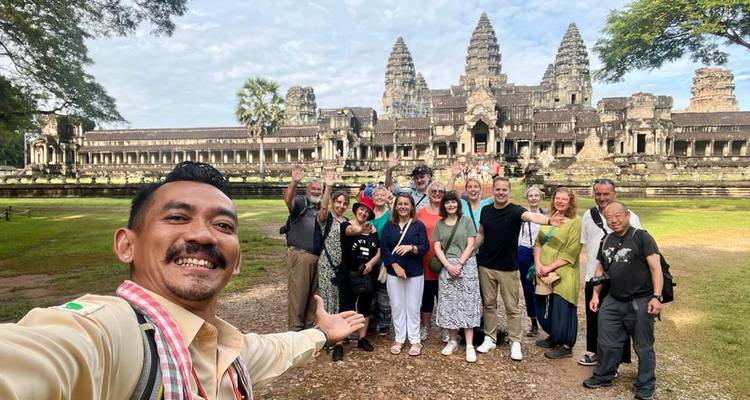 Glimlachende toeristengroep die een selfie neemt voor de iconische torens van het Angkor Wat tempelcomplex.