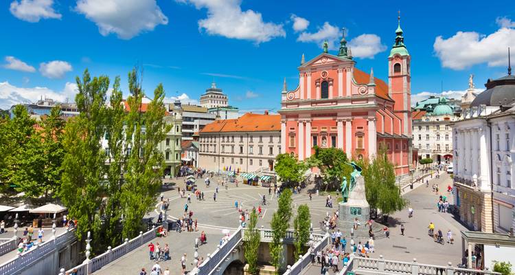 Centre-ville de Ljubljana avec une place bondée et une église rose.