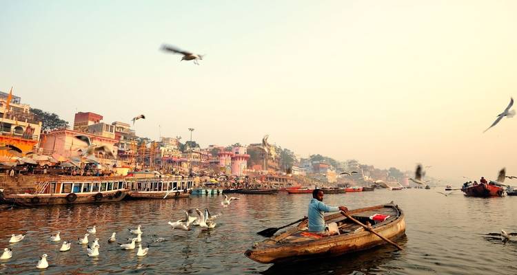Szene mit Booten und Vögeln am Ganges bei Sonnenaufgang.