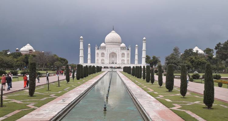 Straight-on view of the Taj Mahal and long reflecting pool under a moody gray sky.