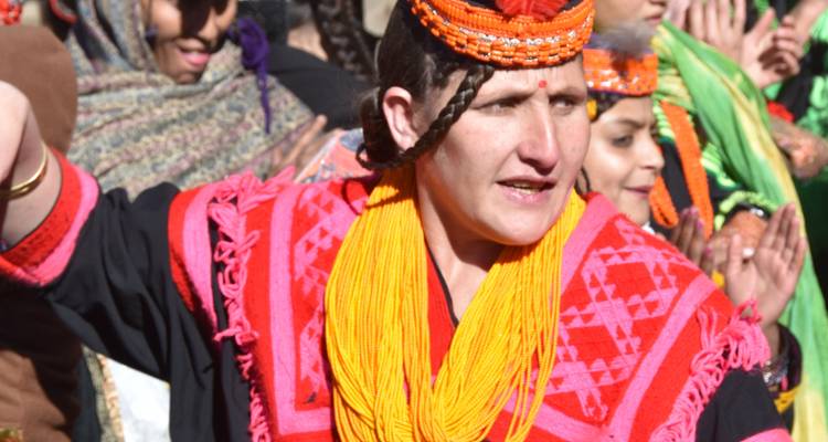 Person in bunter traditioneller Kleidung, die an einem Fest teilnimmt.