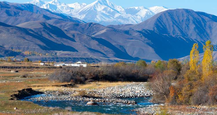 Rivière coulant à travers une vallée avec des montagnes enneigées.