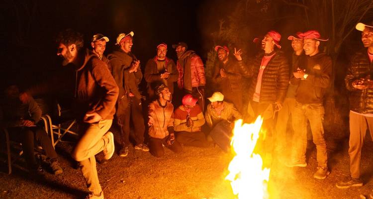 Groupe de personnes profitant d'un feu de camp la nuit.