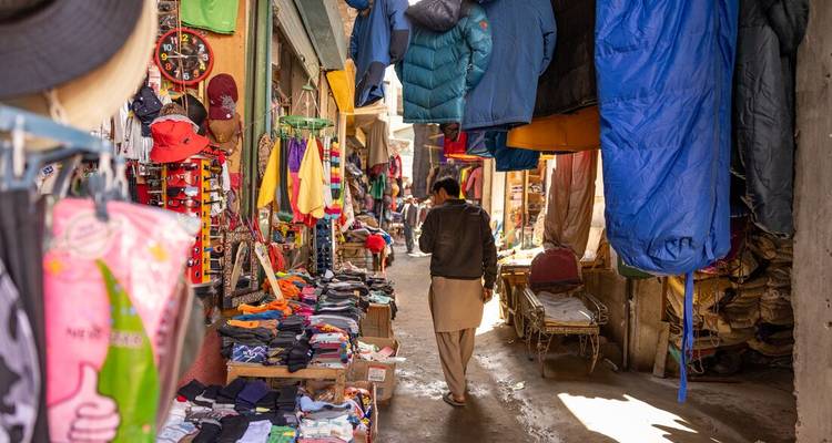 "Ruelle de marché avec des vêtements et divers articles suspendus."