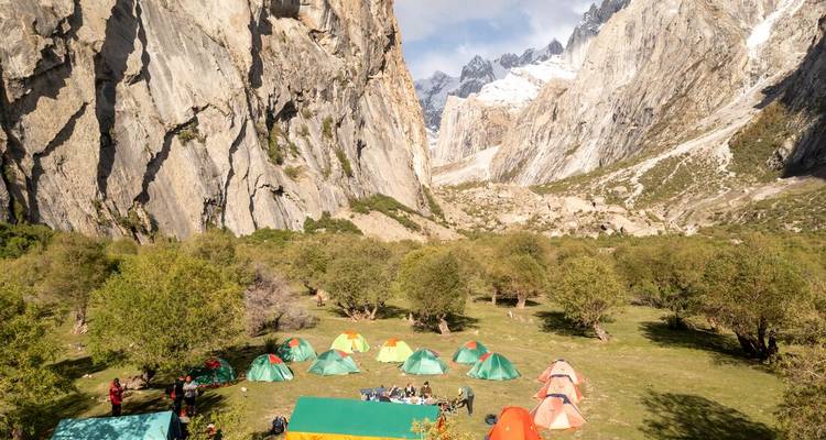 Camping avec tentes entouré de falaises imposantes.