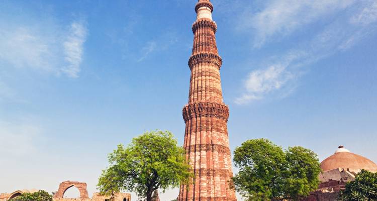 Hoher, kunstvoller historischer Turm vor einem klaren blauen Himmel.