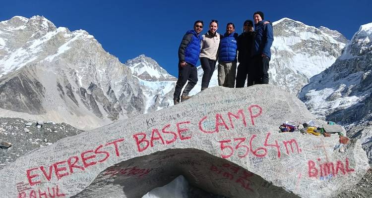 Menschen am Everest-Basislager, die auf einem Felsen stehen.