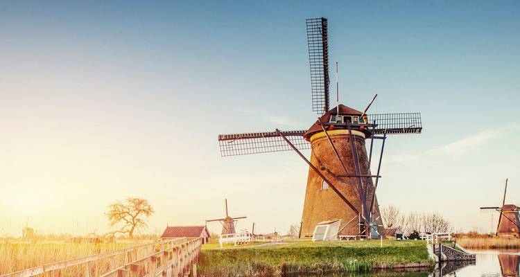 Classic Kinderdijk windmills along a quiet canal bathed in warm evening light.