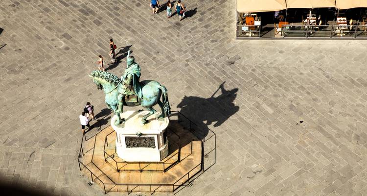 Vue aérienne de la statue équestre en bronze de la Piazza della Signoria projetant une ombre dramatique.