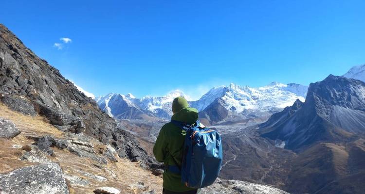 Wanderer mit einem Rucksack vor einem Panoramablick auf schneebedeckte Berge.