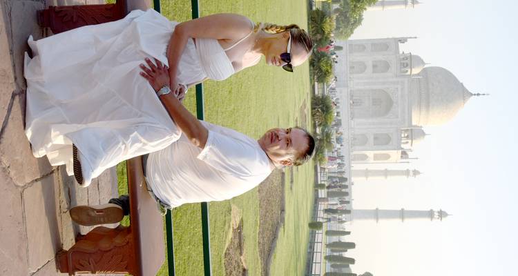 Couple sitting on a bench with Taj Mahal in the background.