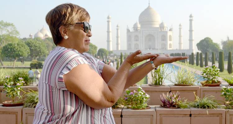 Woman posing with hands up seemingly holding the Taj Mahal.
