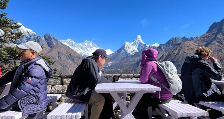 Mensen die aan buitentafels zitten met bergen op de achtergrond.