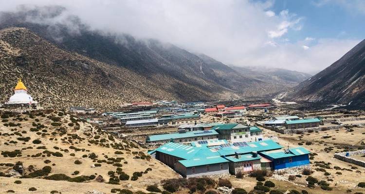 Bergdal met gebouwen en wolken op de achtergrond.