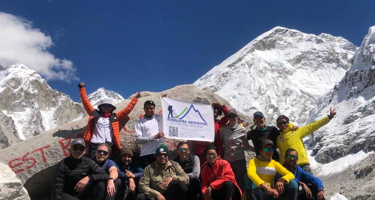 Groep mensen die feest vieren in de bergen, met een spandoek in hun handen.