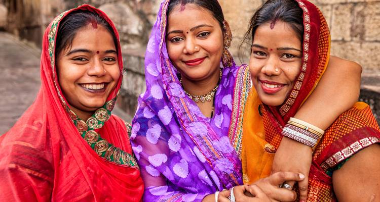 Tres mujeres en vestimenta tradicional sonriendo.