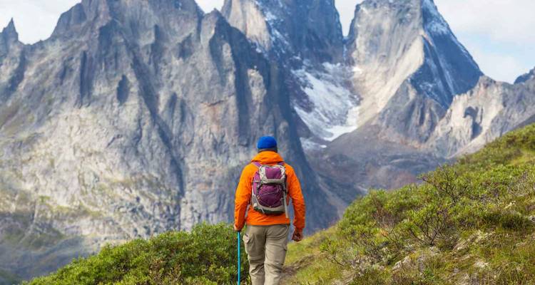 Excursionista acercándose a picos montañosos dramáticos en una zona silvestre.