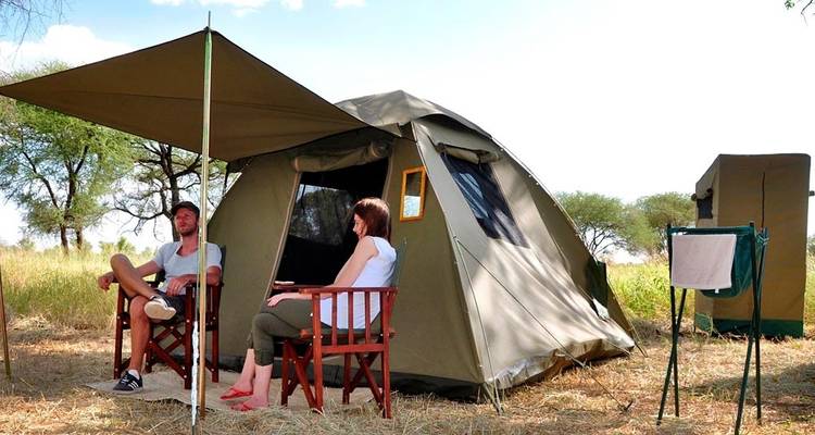 Eine Campingszene mit einem Paar, das vor seinem Zelt sitzt.