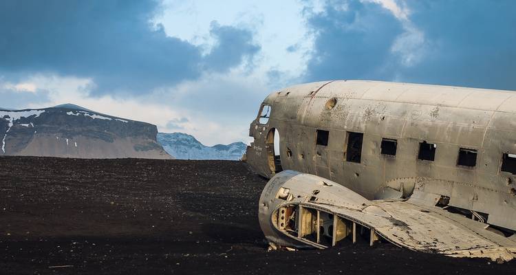 Wreckage of a plane on a rocky, mountainous landscape.