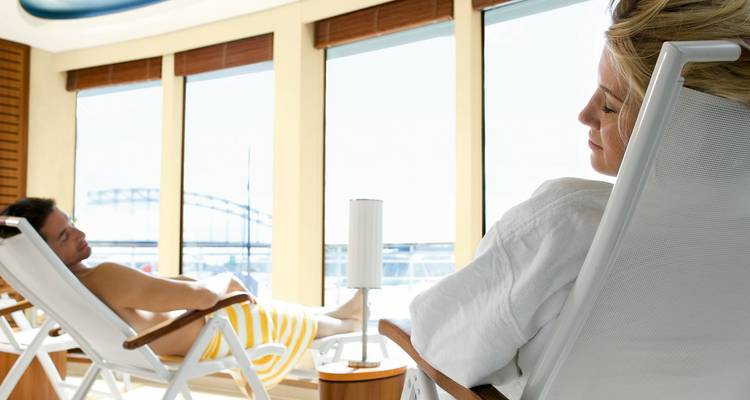 Couple relaxing on loungers in glass-walled spa area of river cruise ship