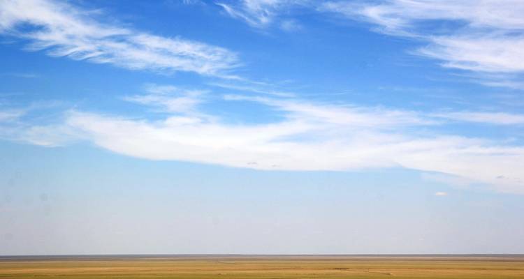 Wijd, vlak landschap met heldere blauwe lucht, geen opvallende kenmerken.
