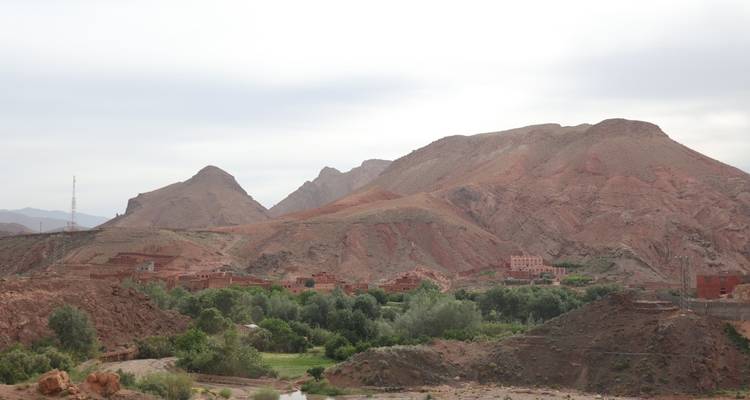 Wüstental mit einer grünen Oase und fernen Bergen.