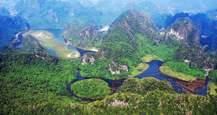 Luftaufnahme von üppig grünen Bergen und sich windenden Flüssen.