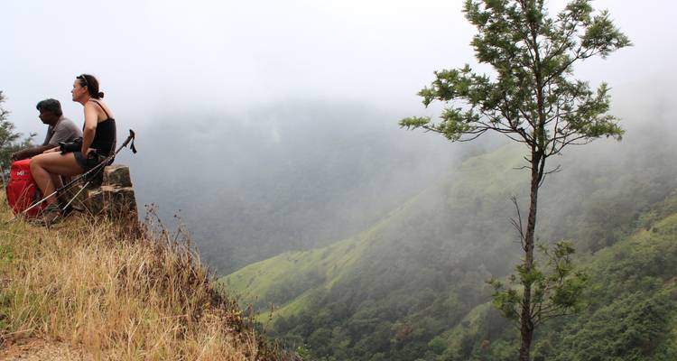 Two people sitting on a mountain edge with a misty background.
