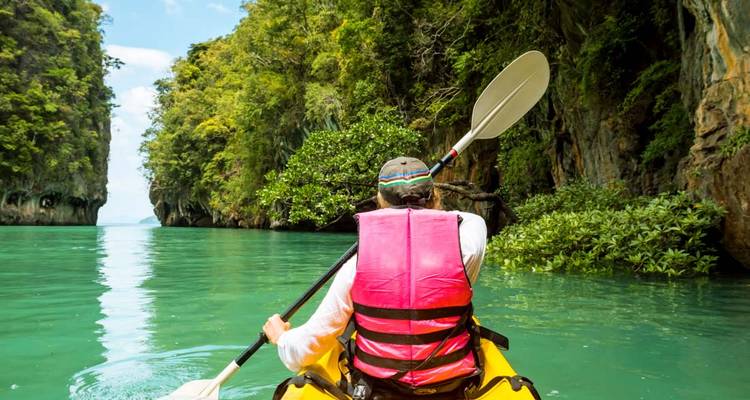 Personne faisant du kayak dans des eaux émeraude avec des falaises pittoresques.