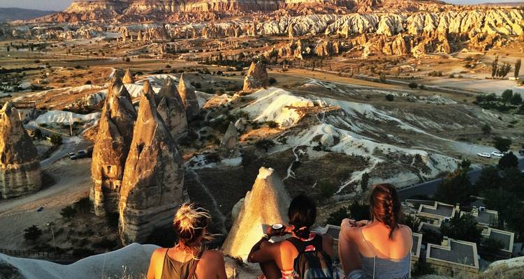 People sitting on a rock overlooking Cappadocia's unique landscape.