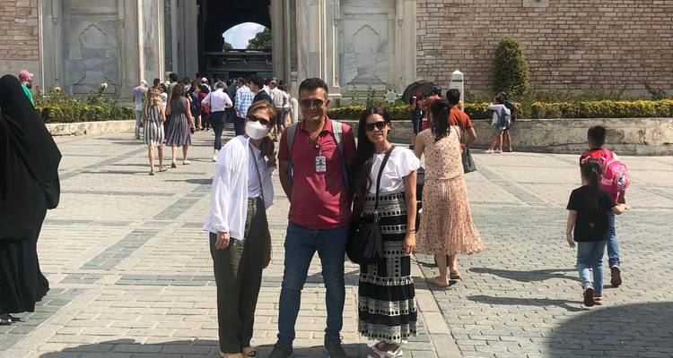 Groupe de personnes posant devant un bâtiment historique et une cour aux murs sculptés.