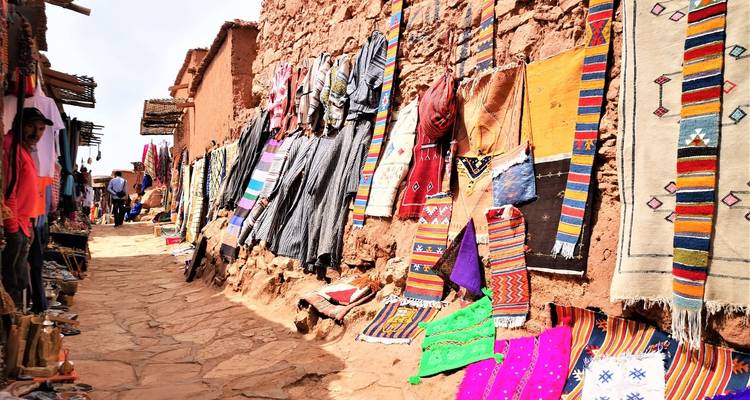 Smalle straat met kleurrijke textiel uitgestald.