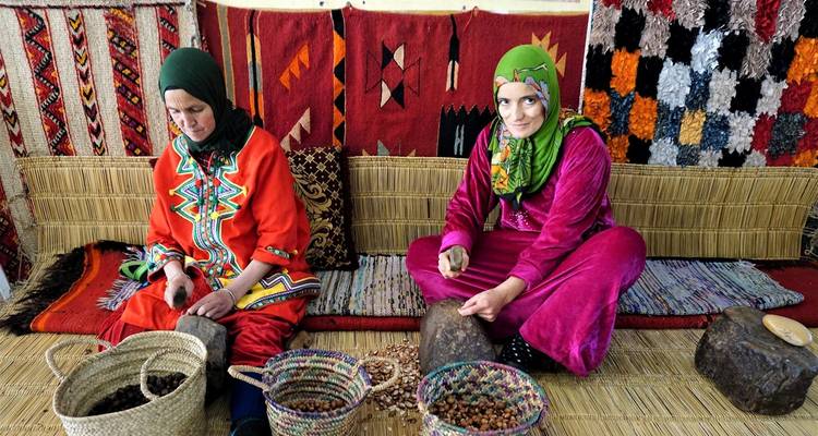 Vrouwen in kleurrijke traditionele kleding die noten sorteren.